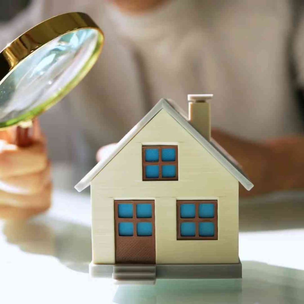 Magnifying glass examining a model home, representing FHA loan benefits