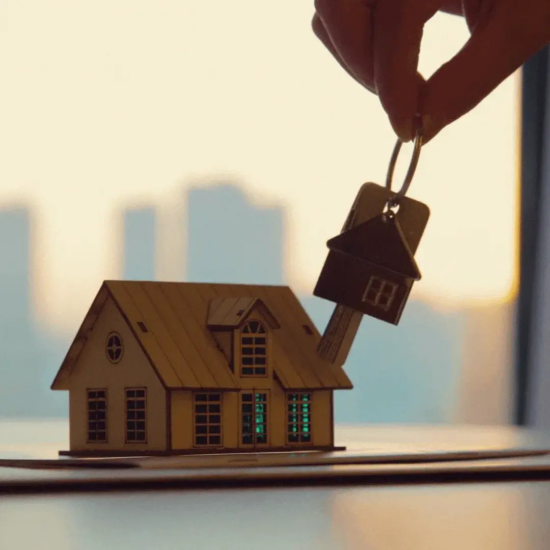 Hand placing a house-shaped key on a model house
